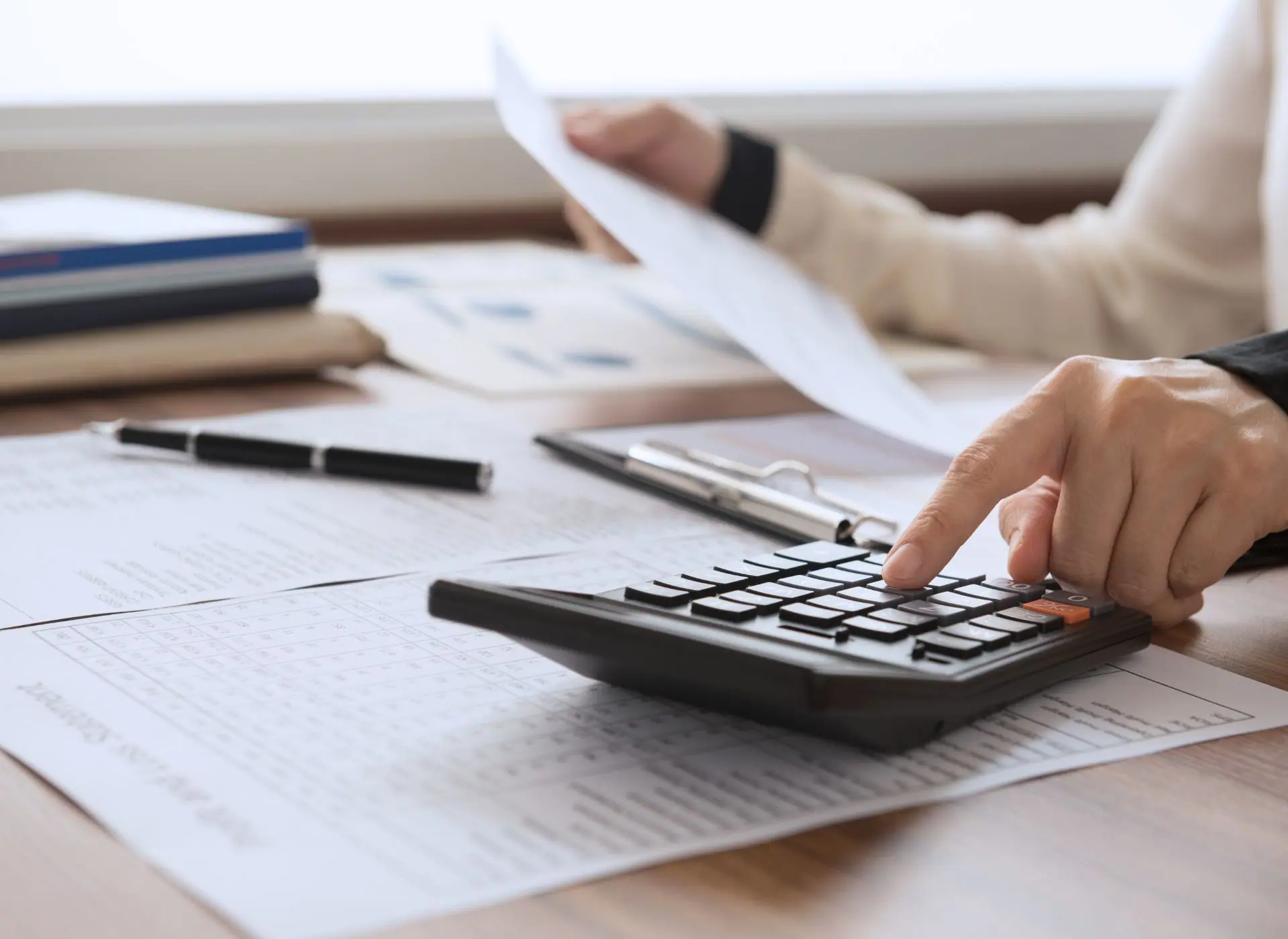 Persona consultando documentos con calculadora
